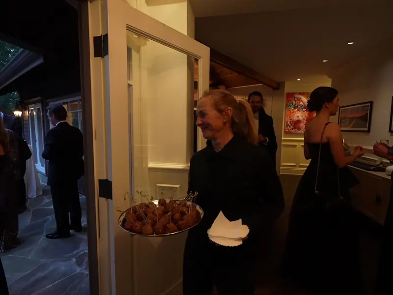 Server passing trays of appetizers to guests at a Stanford reception