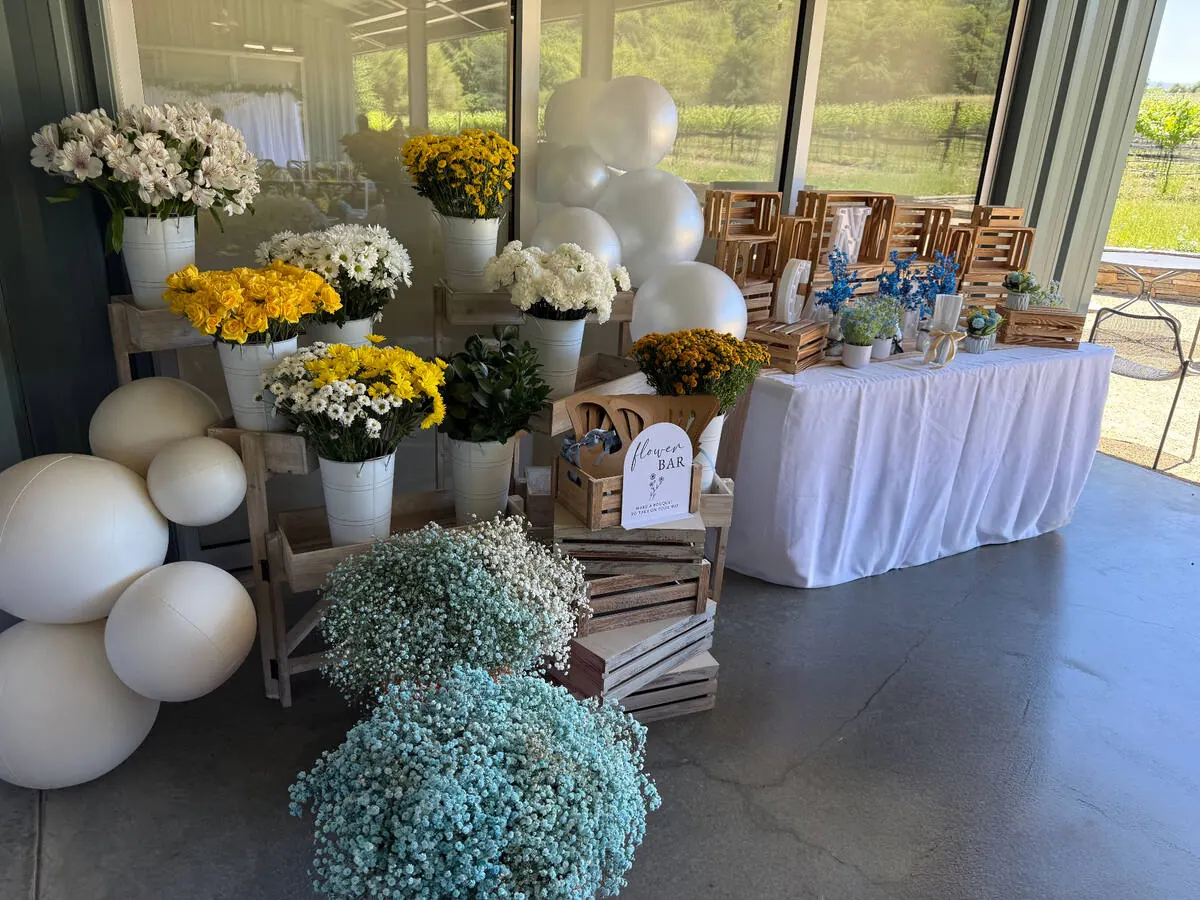 Bloom bar of buckets filled with yellow roses, daisies and baby's breath ready for guests to wrap take-home bouquets — signature bloom bar from our Mountain View catering team