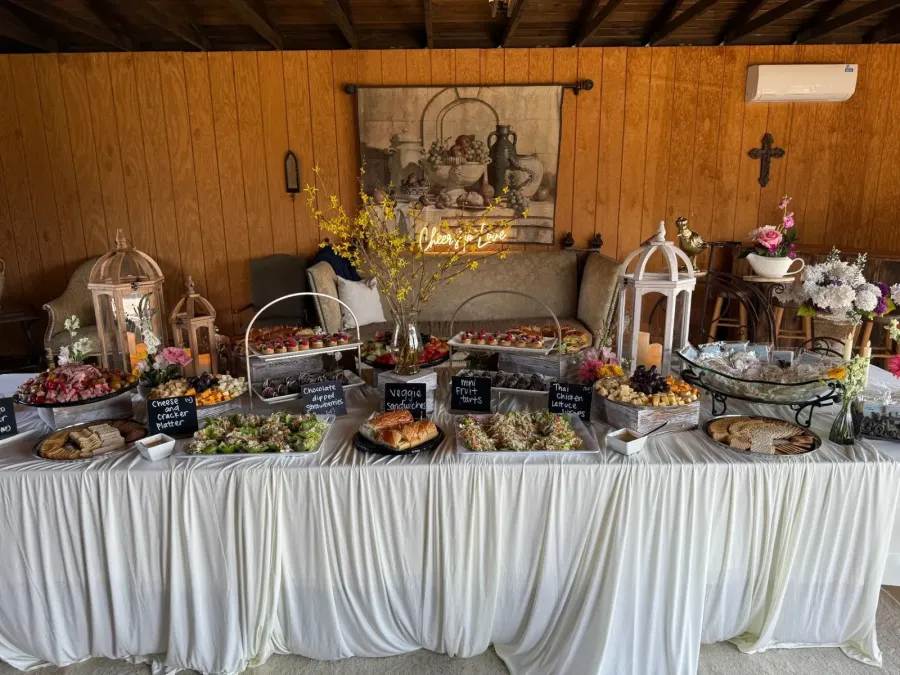 Grazing tablescape of sliced meats, tea sandwiches, fruit tarts and chilled salads pulled together with coordinated linens — grazing styling for Cupertino catering gatherings