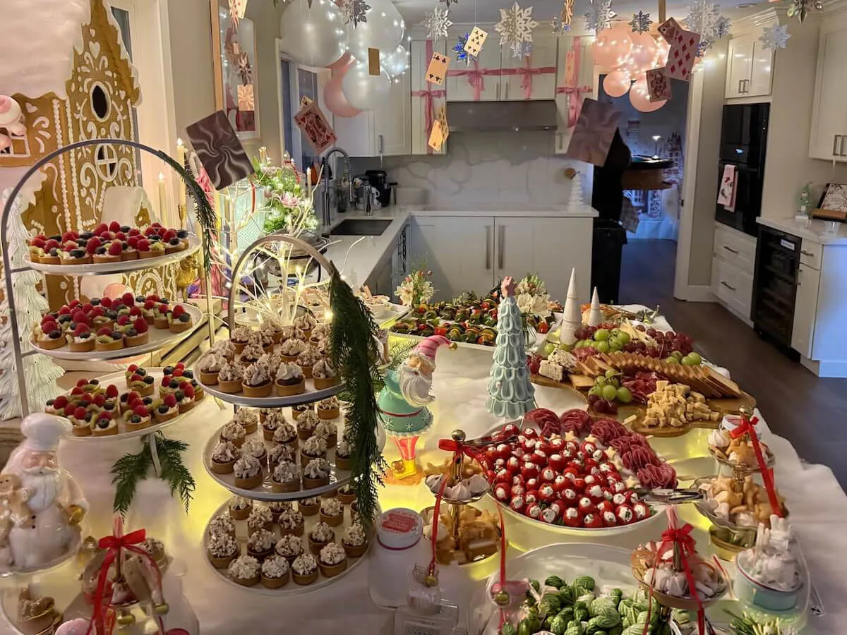 Styled celebration tablescape layering tiered tarts, frosted cupcakes and charcuterie beneath pastel balloon decor — full tablescape design for Santa Clara catering parties