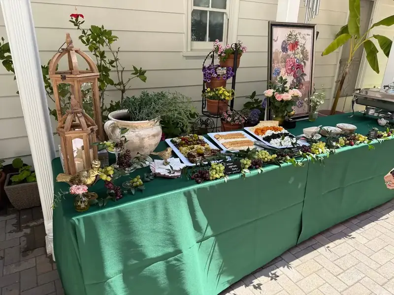 Mountain View celebration spread from Winslow’s Catering with cheese boards, small bites, greenery, flowers, and emerald linens.