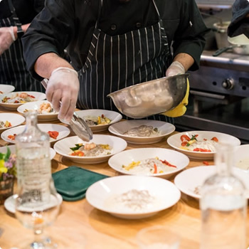 A chef is putting a topping on the dinner plates